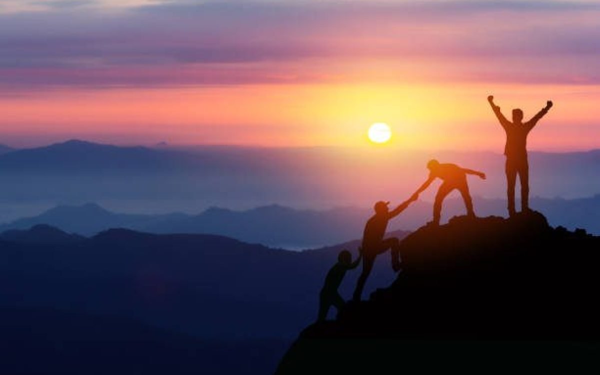 Teamwork friendship hiking help each other trust assistance silhouette in mountains, sunrise. Teamwork of two men hiker helping each other on top of mountain climbing team beautiful sunrise landscape
